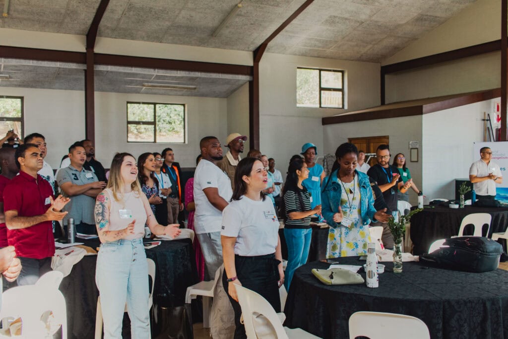 Diverse group of people attending a World Methodist Evangelism event in a conference room.