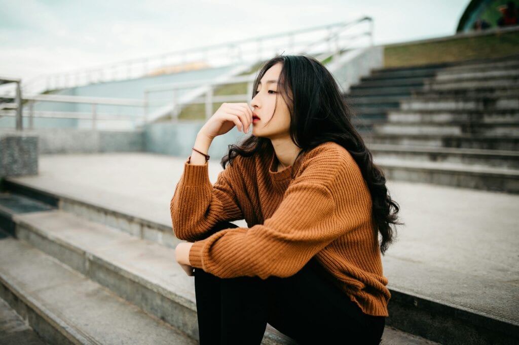 Thoughtful young woman sitting on steps, reflecting at an outdoor venue.