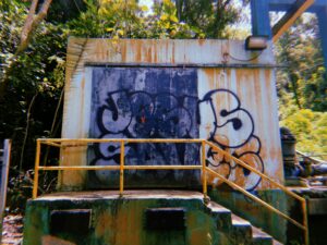 Graffiti-covered rusted metal structure at abandoned industrial site.