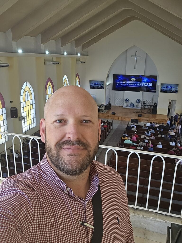Man speaking at church conference inside a Methodist church with congregation.