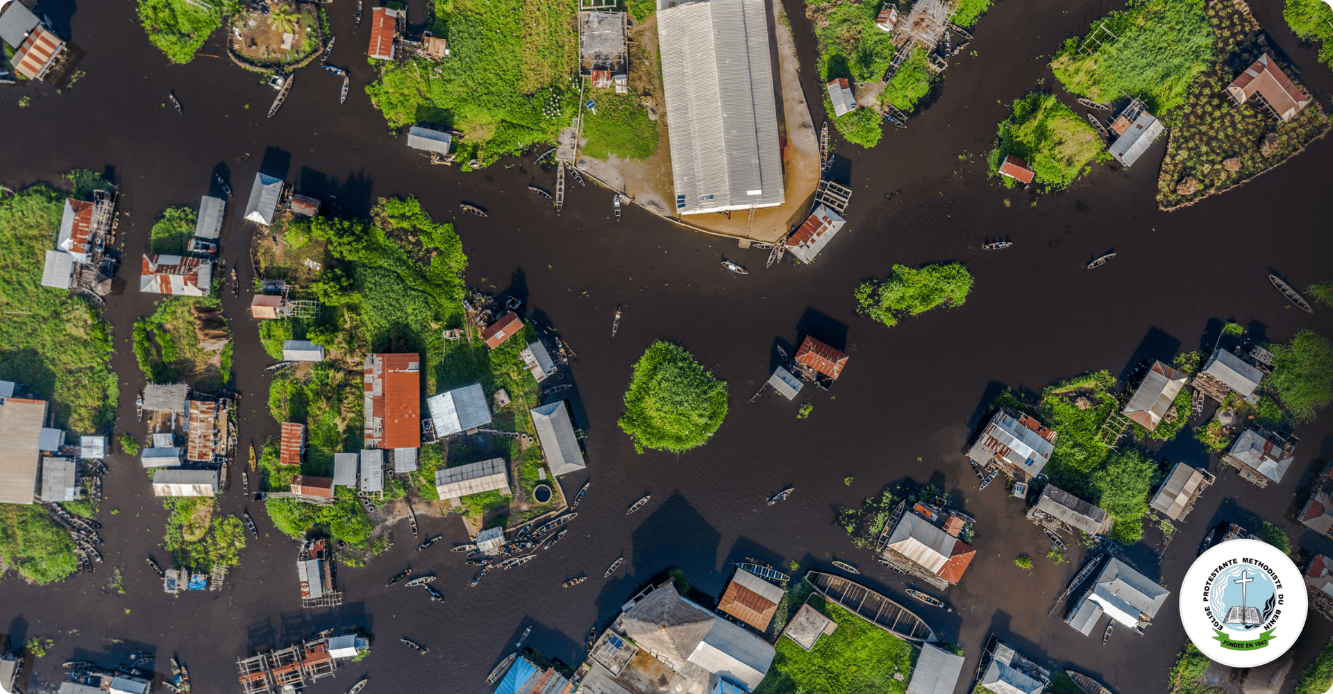 Aerial view of a flooded neighborhood with houses and trees, representing community outreach and res.