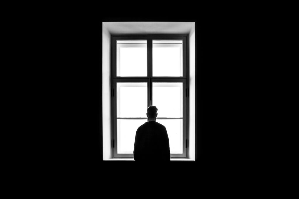 Person looking out of a window symbolizing faith and outreach in World Methodist Evangelism.