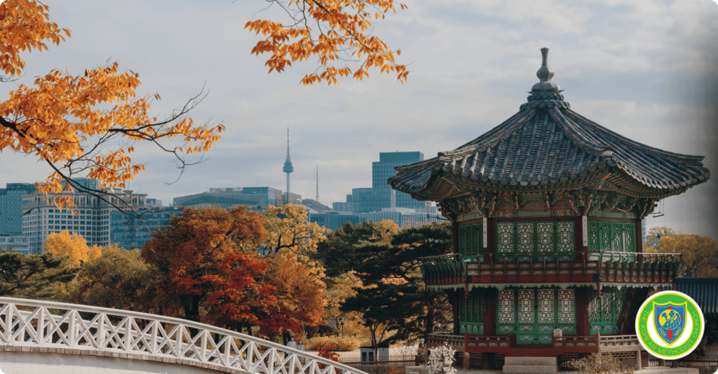 Traditional Korean pavilion with city skyline and autumn trees in Seoul.