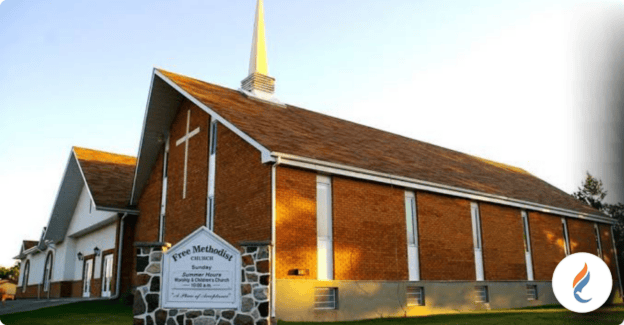 Exterior view of a Methodist church with a steeple and brick walls.