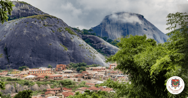 Scenic view of a mountain village with lush greenery and rocky peaks.
