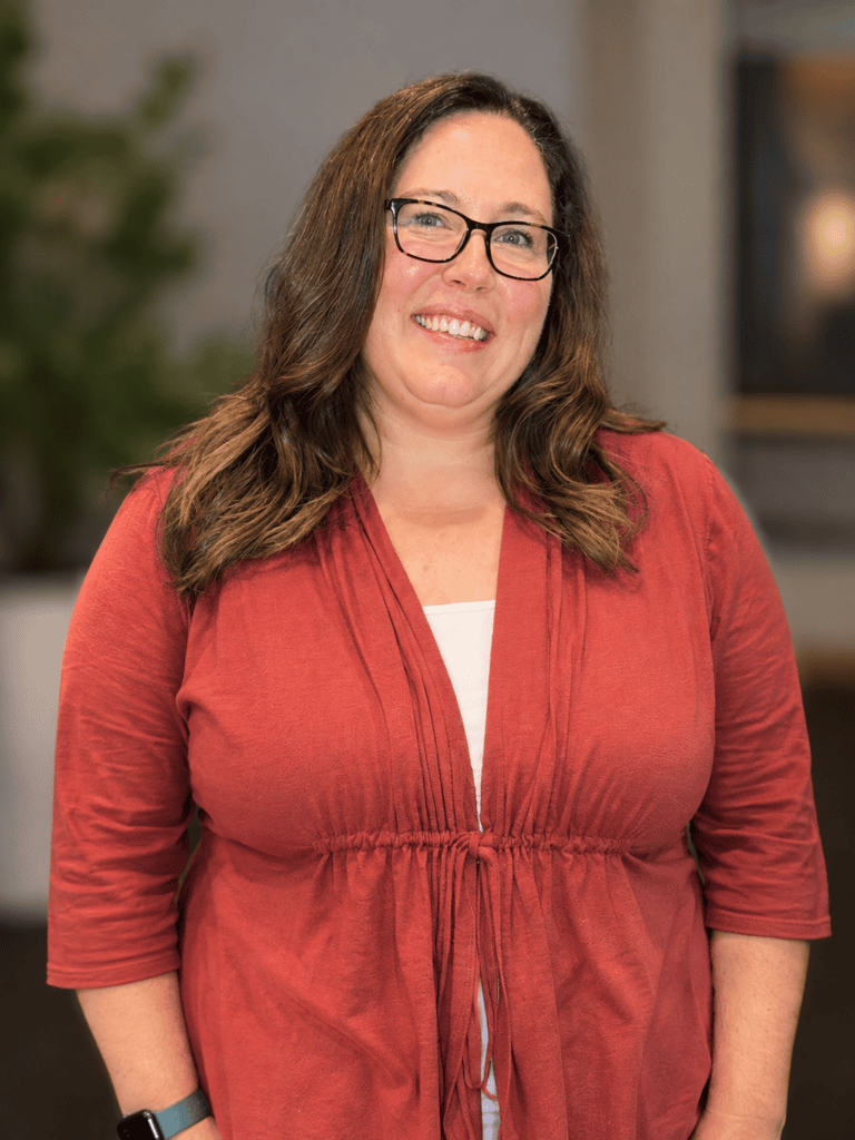 Woman smiling at World Methodist Evangelism event, wearing red top and glasses.