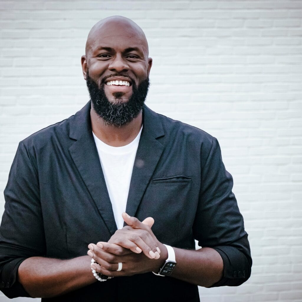 Smiling man with beard in black jacket, promoting evangelism and faith.