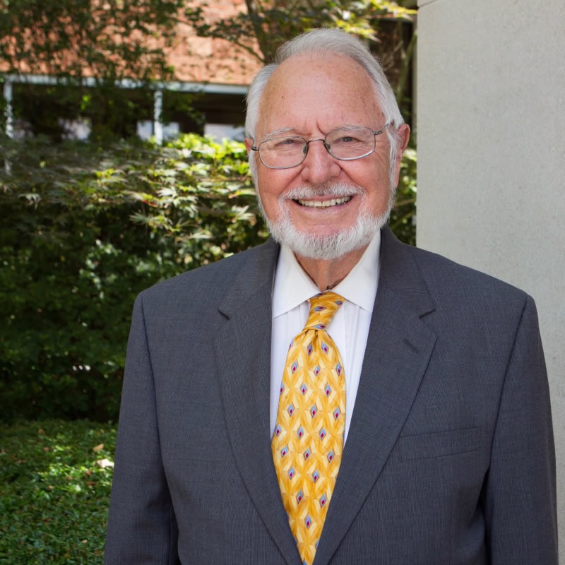 Smiling elderly man in suit and tie outdoors, representing World Methodist Evangelism.